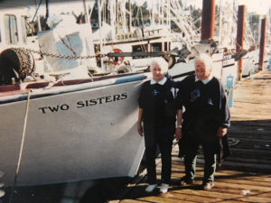 Photo of Adele Wilder and her sister by a boat called "Two Sisters"